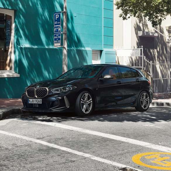 BMW M135i xDrive, vista lateral de tres cuartos. Nuevo BMW M135i xDrive en Black Sapphire metallic; vista lateral de tres cuartos estacionado.