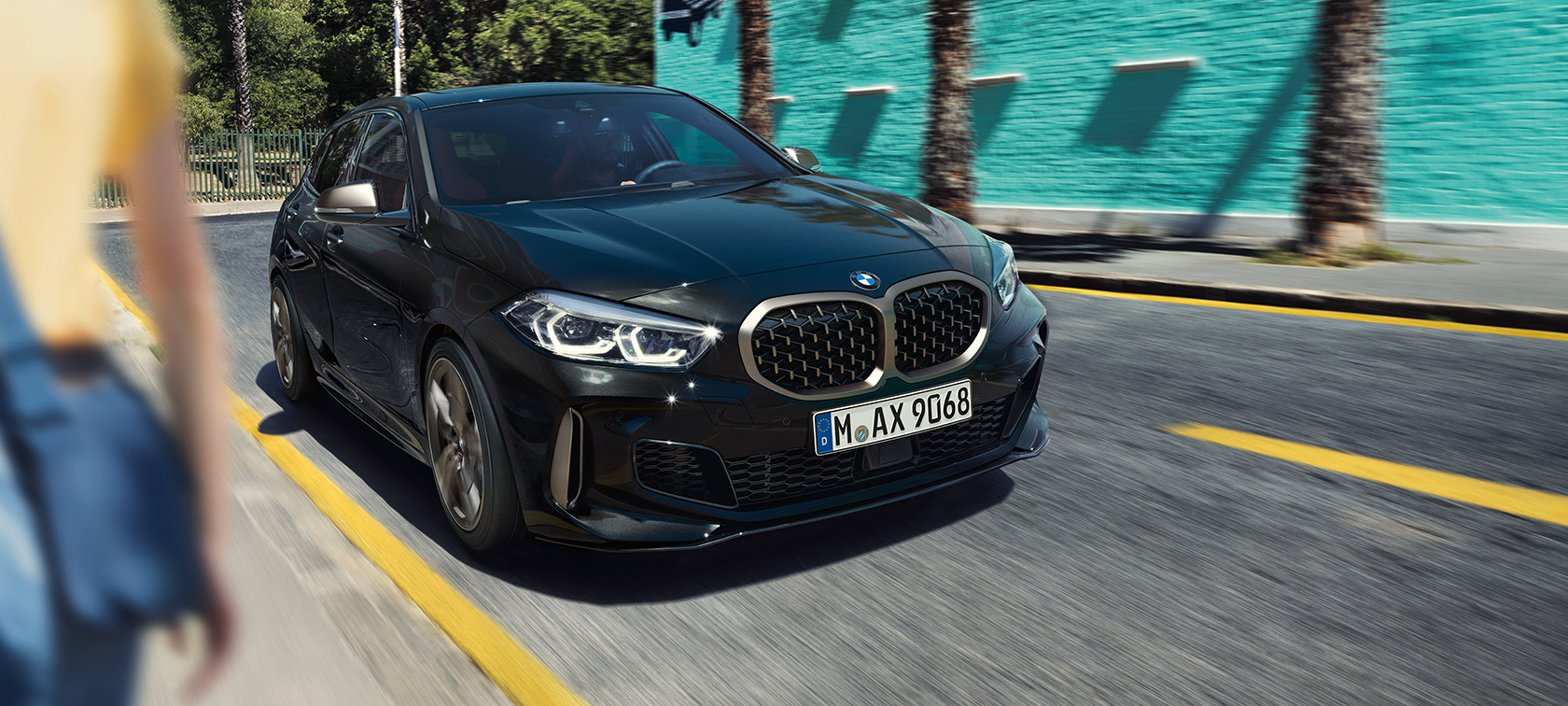 BMW M135i xDrive, vista frontal de tres cuartos. BMW M135i xDrive en Black Sapphire metallic, vista frontal de tres cuartos en movimiento.