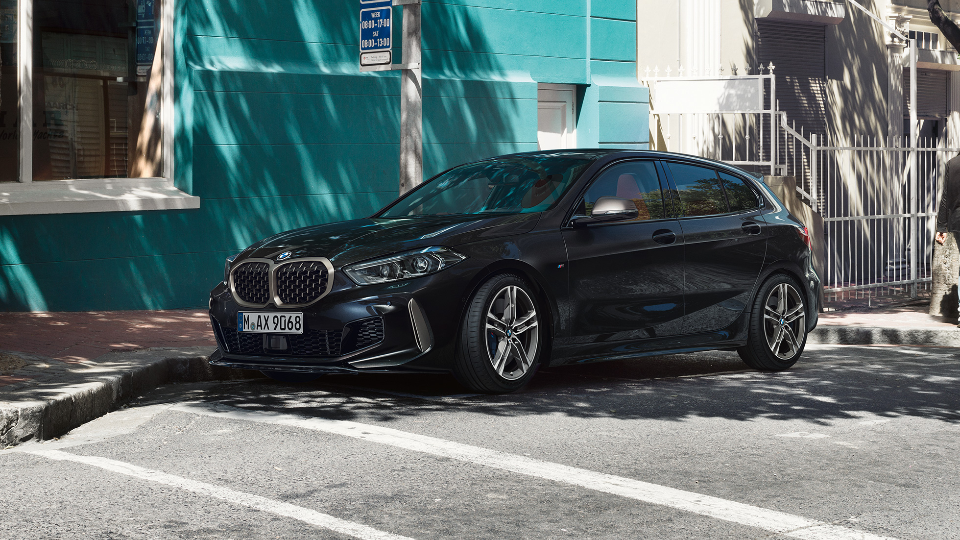 BMW M135i xDrive, vista lateral de tres cuartos. Nuevo BMW M135i xDrive en Black Sapphire metallic; vista lateral de tres cuartos estacionado.